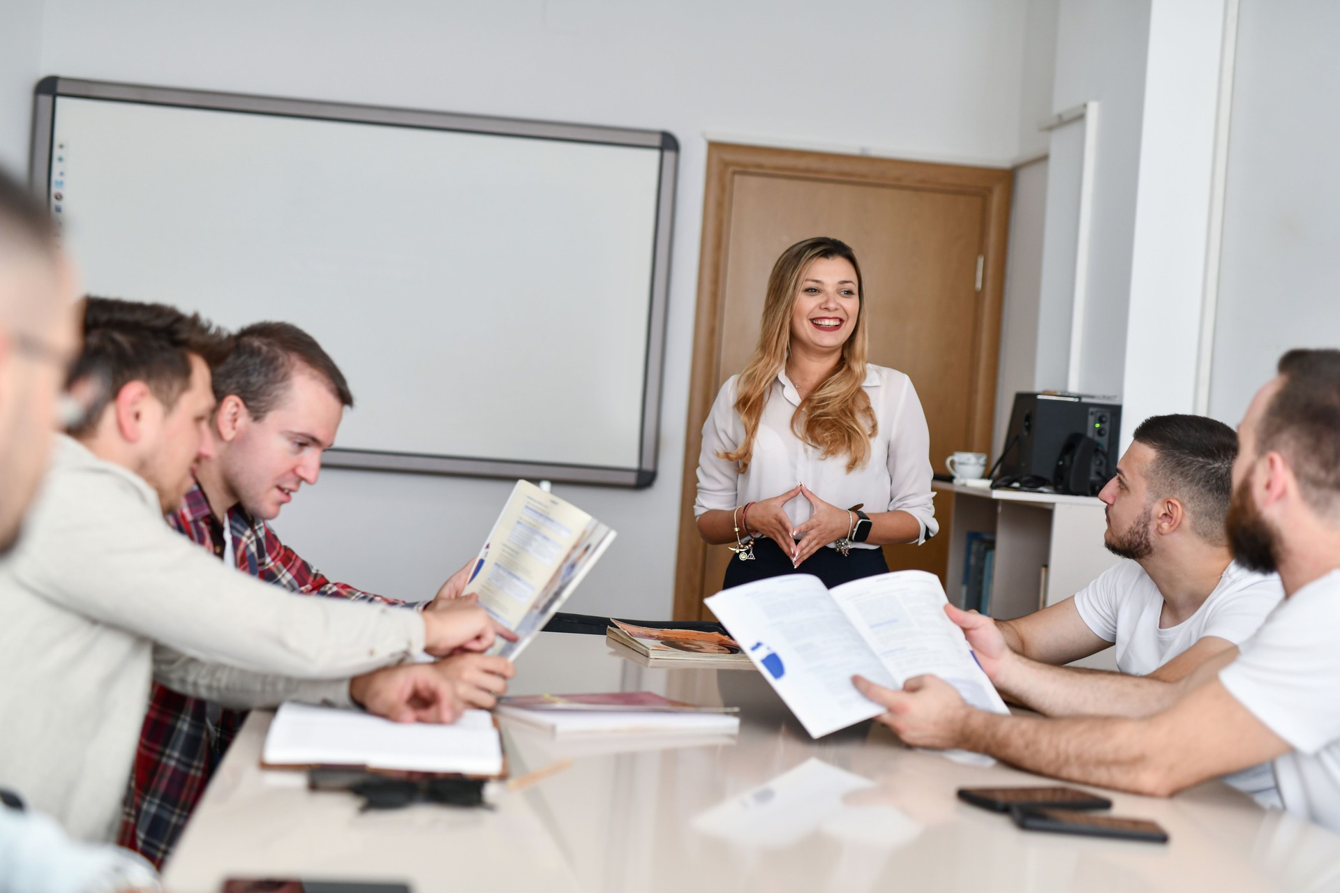 Group of Male Adults Focused on Their Books Carefully Listening to Their Teacher on Night English Class