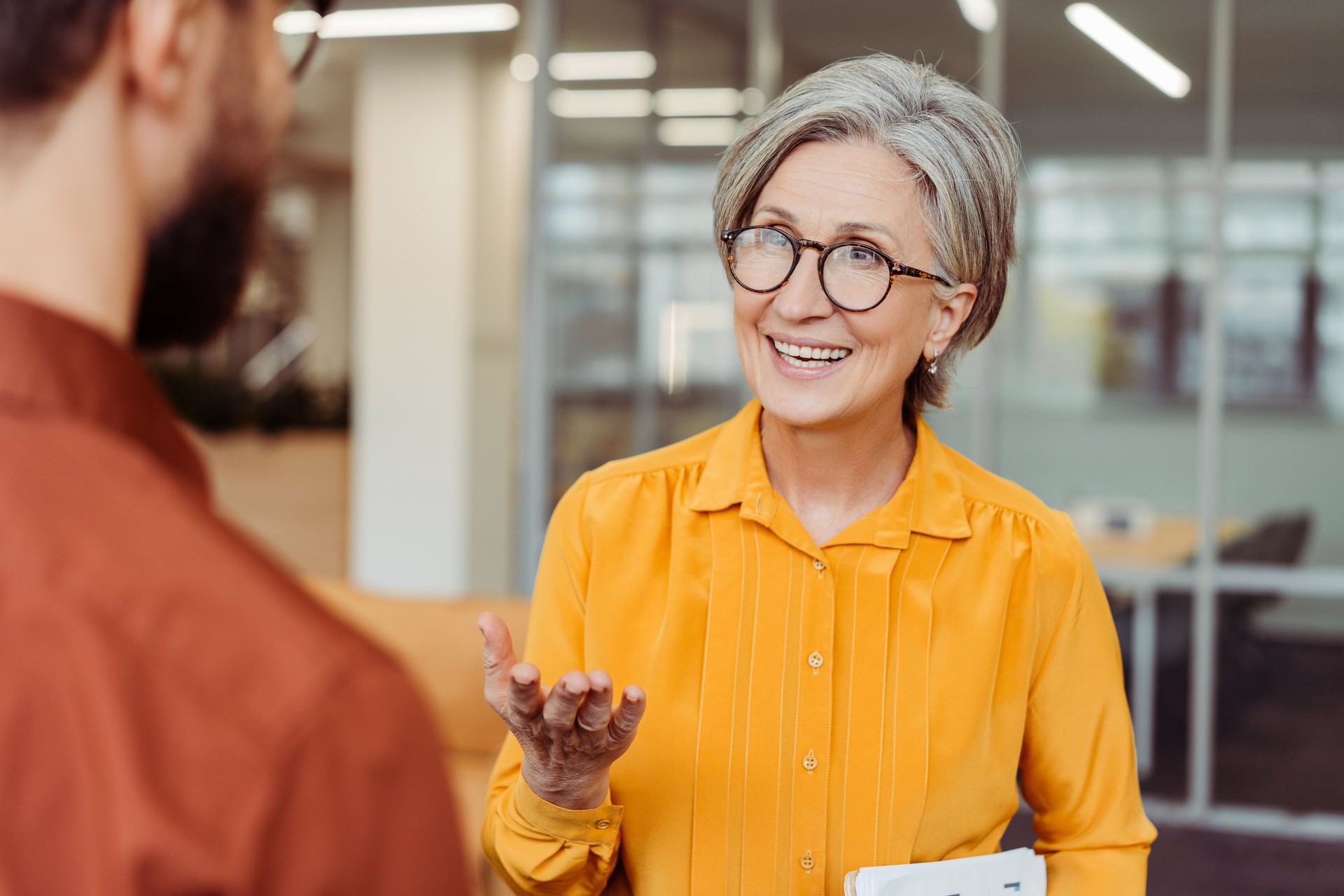 Smiling confident senior woman communication with colleague at workplace. Meeting, teamwork