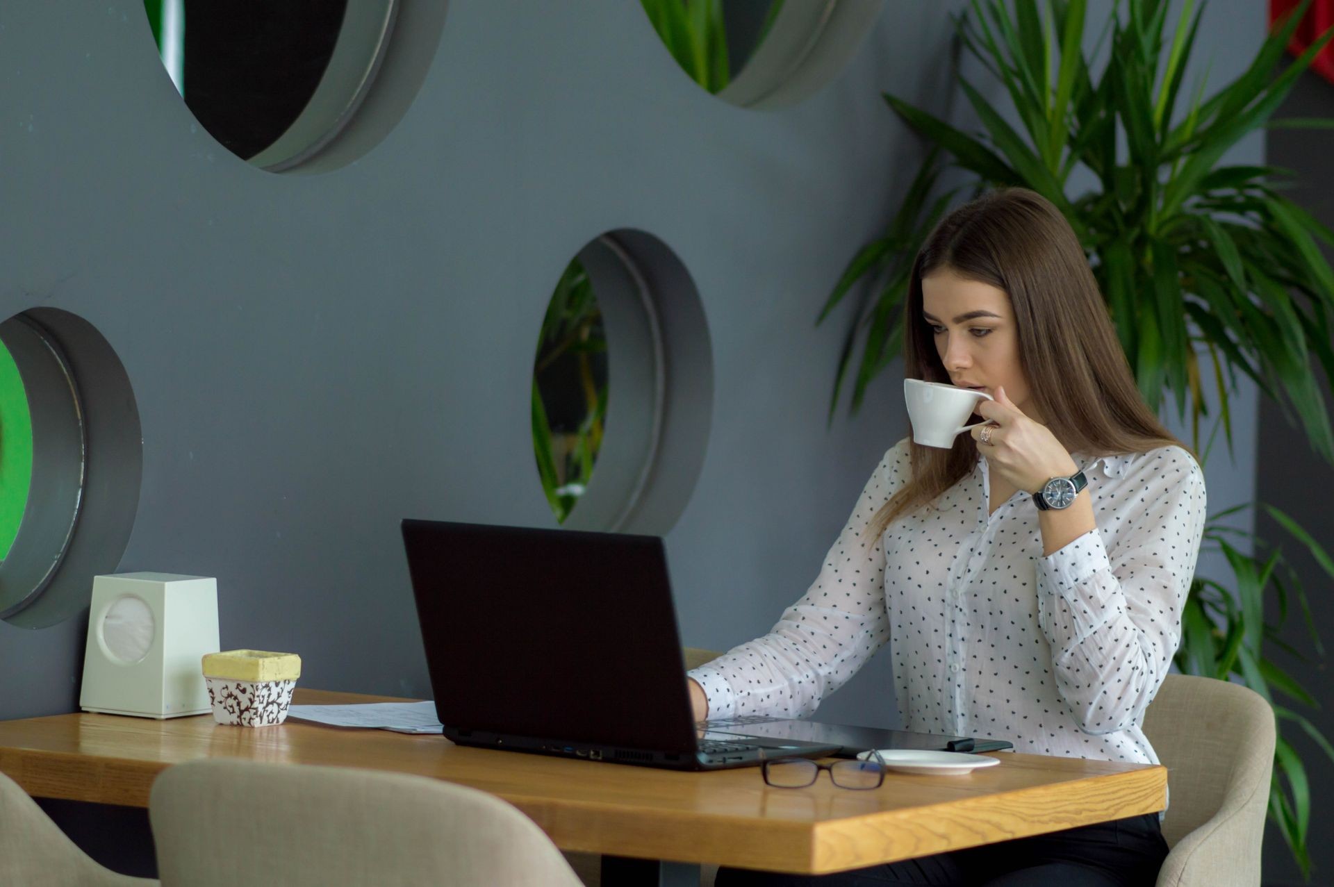 
Portrait of a pretty young woman studying while seated in a cafe with laptop computer and tablet computer. 
Remote online training session